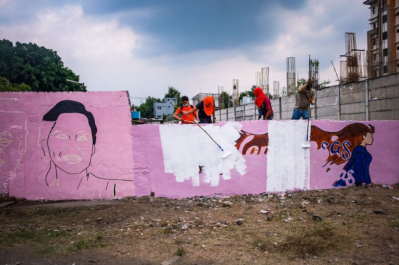 Men with t-shirts of Senate candidate Mark Villar of the Hugbong Pagbabago Party smear a wall with paintings campaigning for Presidential candidate Leni Robredo and Vice-Presidential candidate Kiko Pangilinan in Las Pinas. (Picture: Yummie Dingding)