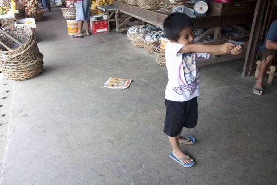 Ein Junge hält eine Spielzeugwaffe auf einem Marktplatz